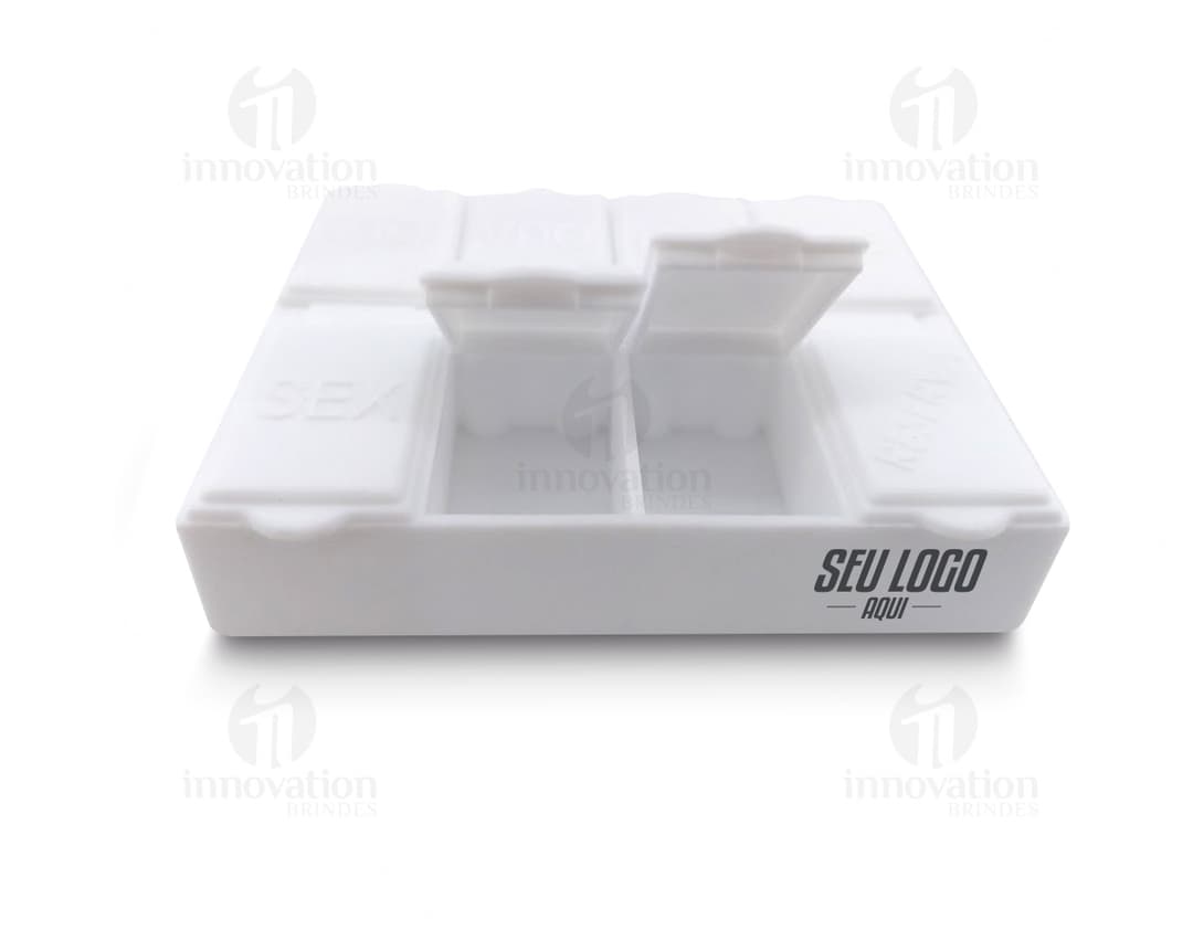 Porta comprimidos de plástico transparente com sete divisórias rotuladas com os dias da semana.