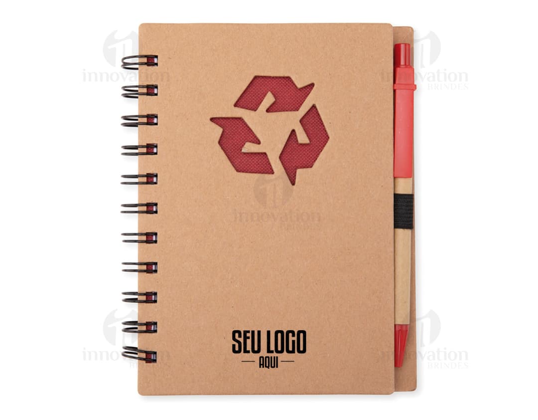 Caderno ecológico com caneta sobre uma mesa de escritório, ao lado de um papel em branco, uma mensagem escrita, um objeto de escritório e uma página de documento vazia. A imagem mostra um caderno vazio com espaço para escrever, ideal para anotações e lembretes no ambiente de trabalho.