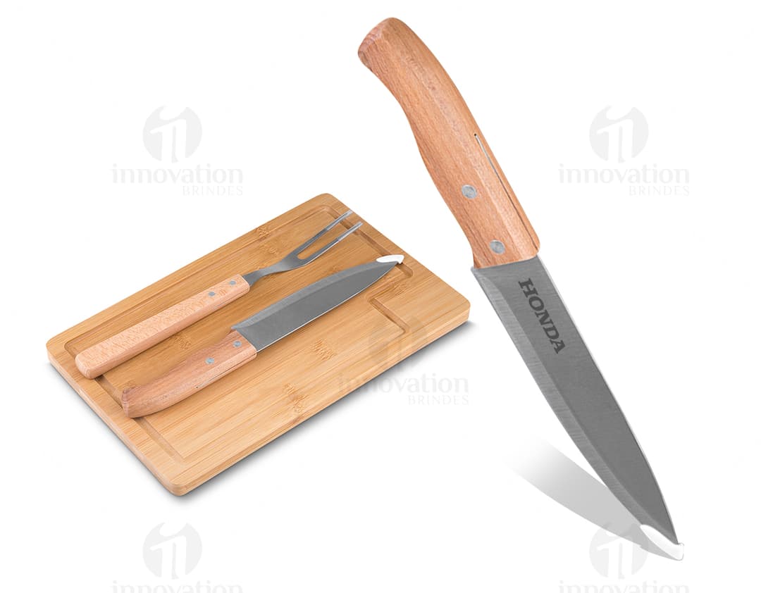 Kit churrasco composto por 3 peças (faca, garfo e espátula) e uma tábua de madeira.