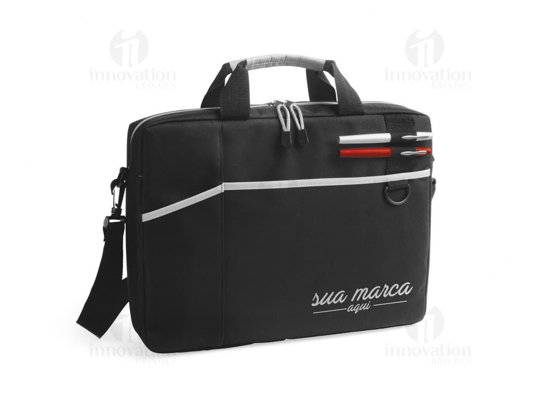 Fotografia de uma pasta preta para notebook de 15,6 polegadas, feita em couro 600D almofadado, com alça, fecho de zíper, botão de metal e bloqueio. O acessório possui um design elegante e moderno, indicado para viagens de negócios e uso pessoal.