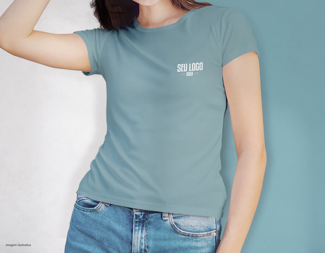 Camiseta feminina de corte cinturado em cor azul, usada por uma modelo sorridente e atraente. Ela está posando de forma casual e elegante, com cabelo escuro e jeans. A roupa é moderna e estilosa, perfeita para mulheres jovens e modernas.