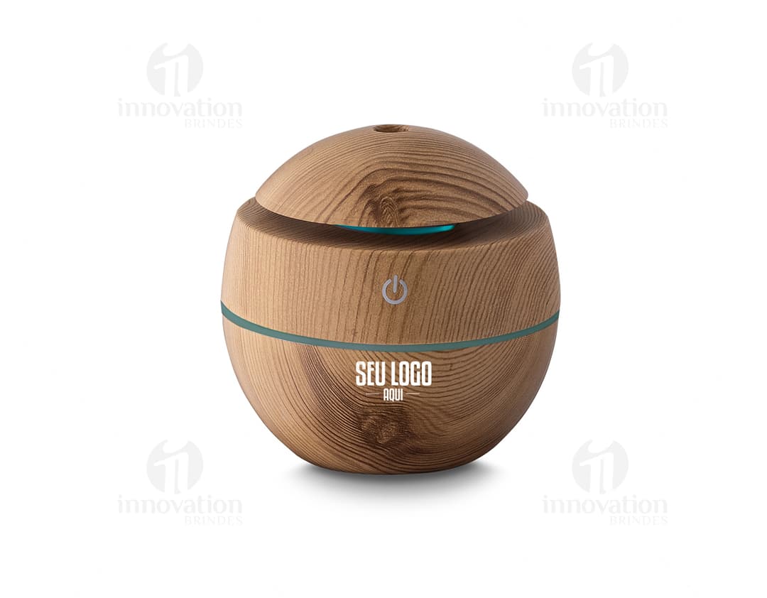 Umidificador de ar USB em ABS reciclável, que aparece em uma cesta de vime marrom ao lado de um banco, comida, dinheiro e outros objetos. A imagem é de vista próxima, com foco no produto e nos detalhes dos materiais utilizados.