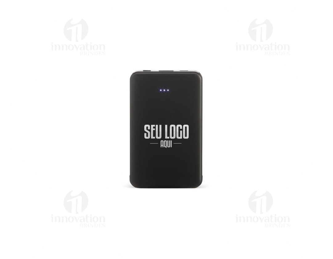 Power Bank Plástico 5.000mAh preto, dispositivo de tecnologia com adaptador e cabo de conexão. Equipamento eletrônico moderno para carregar dispositivos móveis. Visto contra um fundo de papel e teclado de computador.