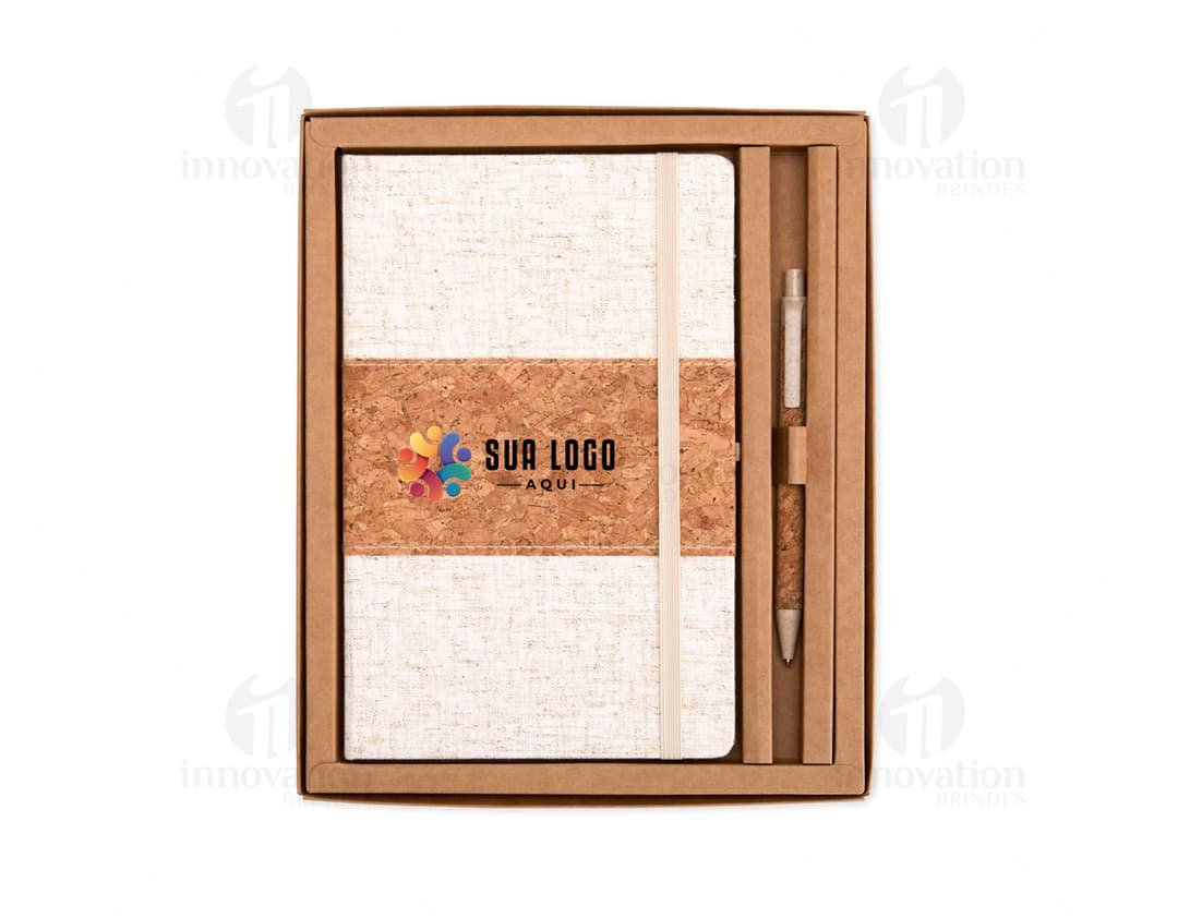 Caixa de papelão marrom antiga e vazia com tampa aberta, contendo um livro de capa dura de cor preta e uma caderneta de papel amarelo, empilhados sobre uma mesa de madeira vintage.