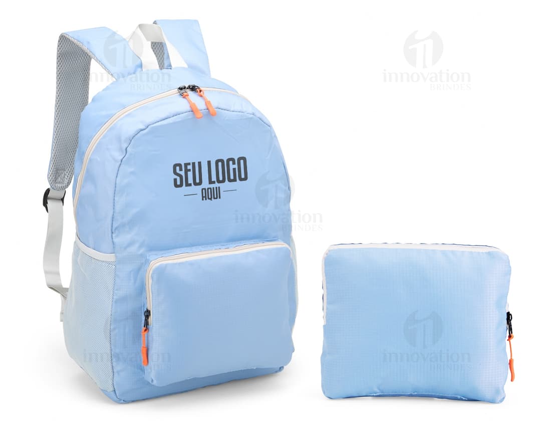 Mochila de Nylon Dobrável 23 Litros preta sendo segurada por um homem sorrindo, em um estúdio. O produto é um equipamento de viagem e possui zíper, alça, e é adequado para hiking, escola, negócios e lazer.