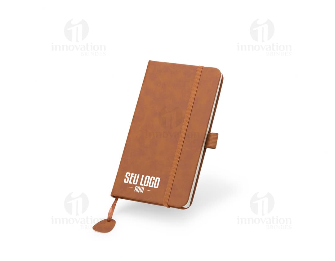 Caderneta Emborrachada com capa azul e elástico, em cima de uma mesa de madeira.