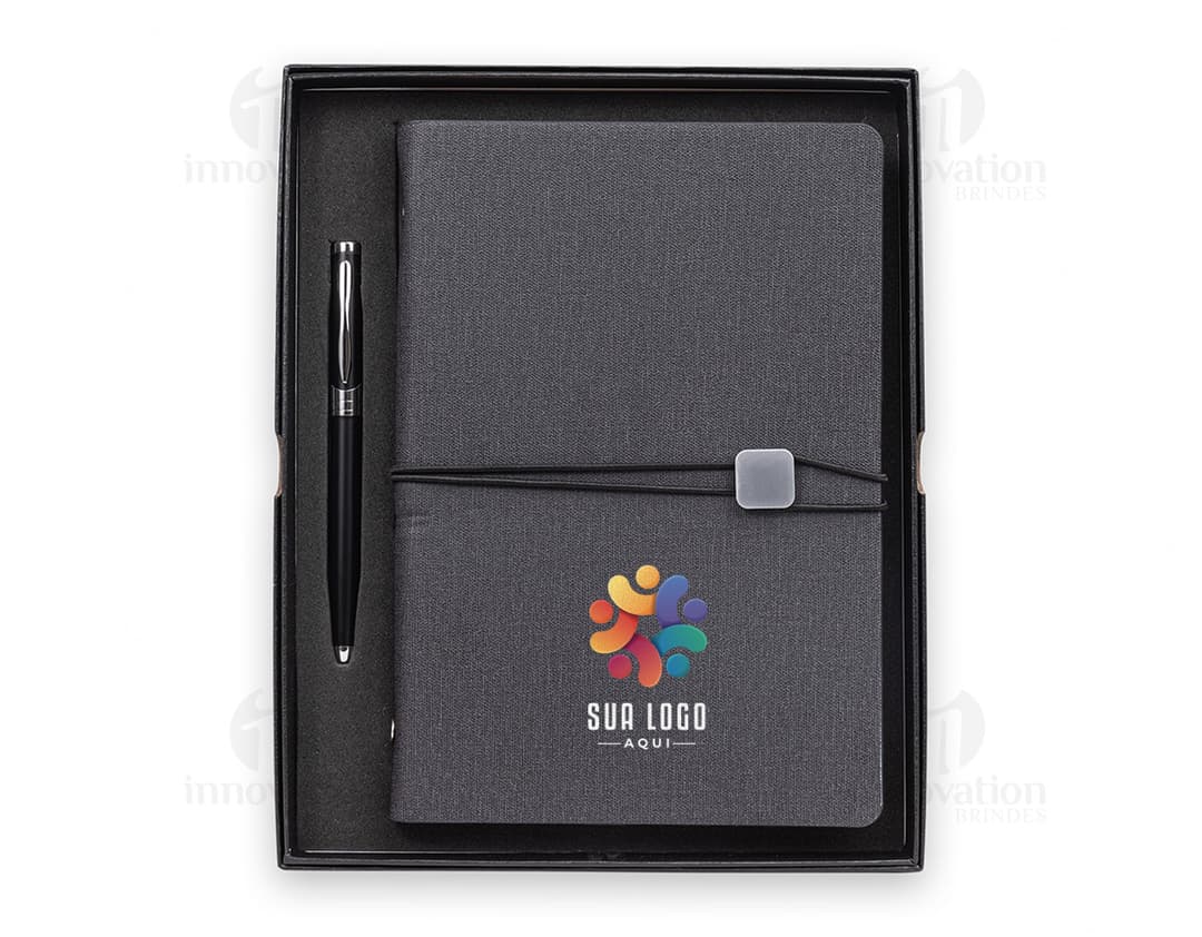 Kit executivo 2 peças composto por uma agenda preta de couro e uma caneta prateada.