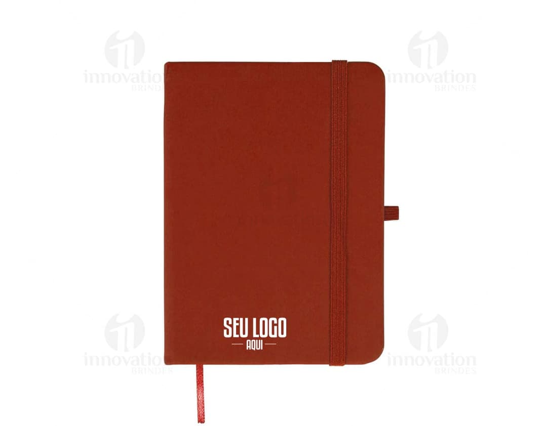 Caderneta emborrachada preta com design vintage, vazia e com textura grunge. Aparecem um notebook, um metrônomo, uma guitarra, uma página em branco e um pendulo.