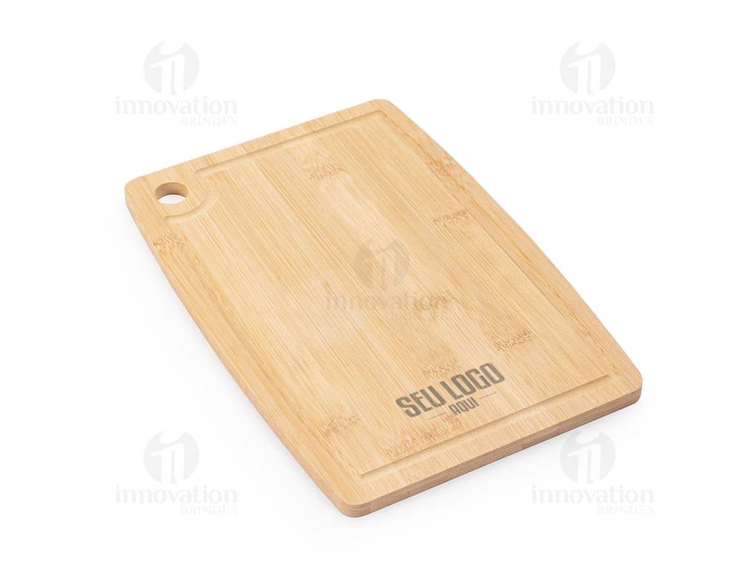 Tábua de corte retangular feita em madeira clara, com uma canaleta na borda para recolher líquidos e restos de alimentos.