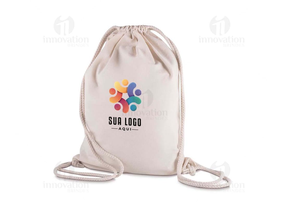 Mochila em algodão: contém uma sacola grande em algodão, de cor clara e resistente. Ideal para transportar objetos, alimentos e bebidas, como garrafas de água e recipientes de plástico. Ótima opção para quem busca praticidade e durabilidade no dia a dia.