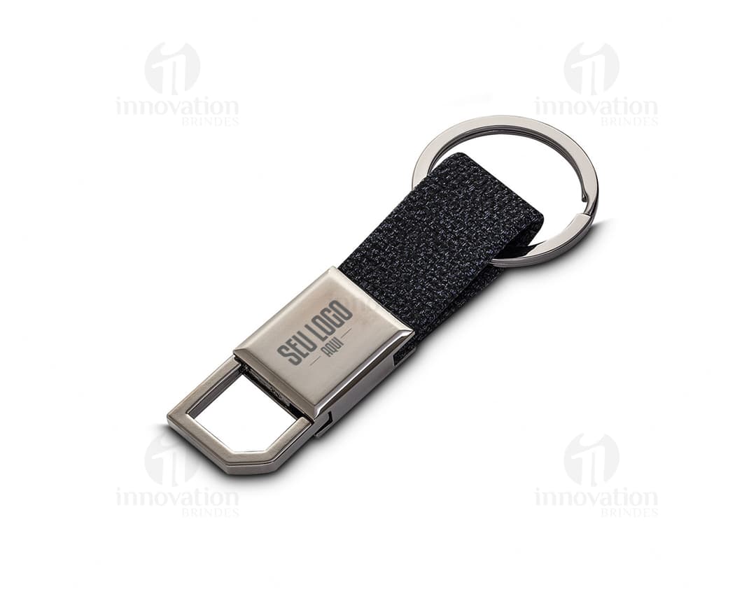 Chaveiro de couro preto com detalhes em metal prateado. Possui um suporte para celular e uma ferramenta cortante embutida. O chaveiro também conta com um display de tela digital, teclado e botões de conexão sem fio. É um acessório moderno e prático para negócios e comunicação.