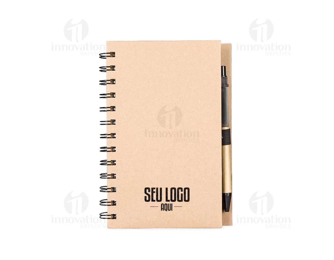 Caderno Ecológico com capa de papel kraft marrom, fecho de elástico e detalhe de folha verde. Páginas internas em papel reciclado.
