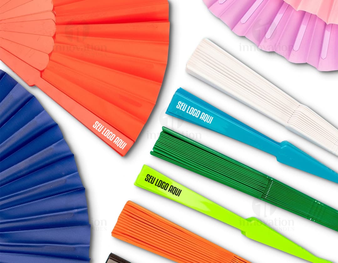 Leque de plástico colorido, com design moderno e brilhante. O leque possui formas geométricas em tons de amarelo, laranja, violeta, rosa e azul, lembrando um arco-íris. É um objeto decorativo e criativo, perfeito para escritórios, bibliotecas ou salas de estudo.