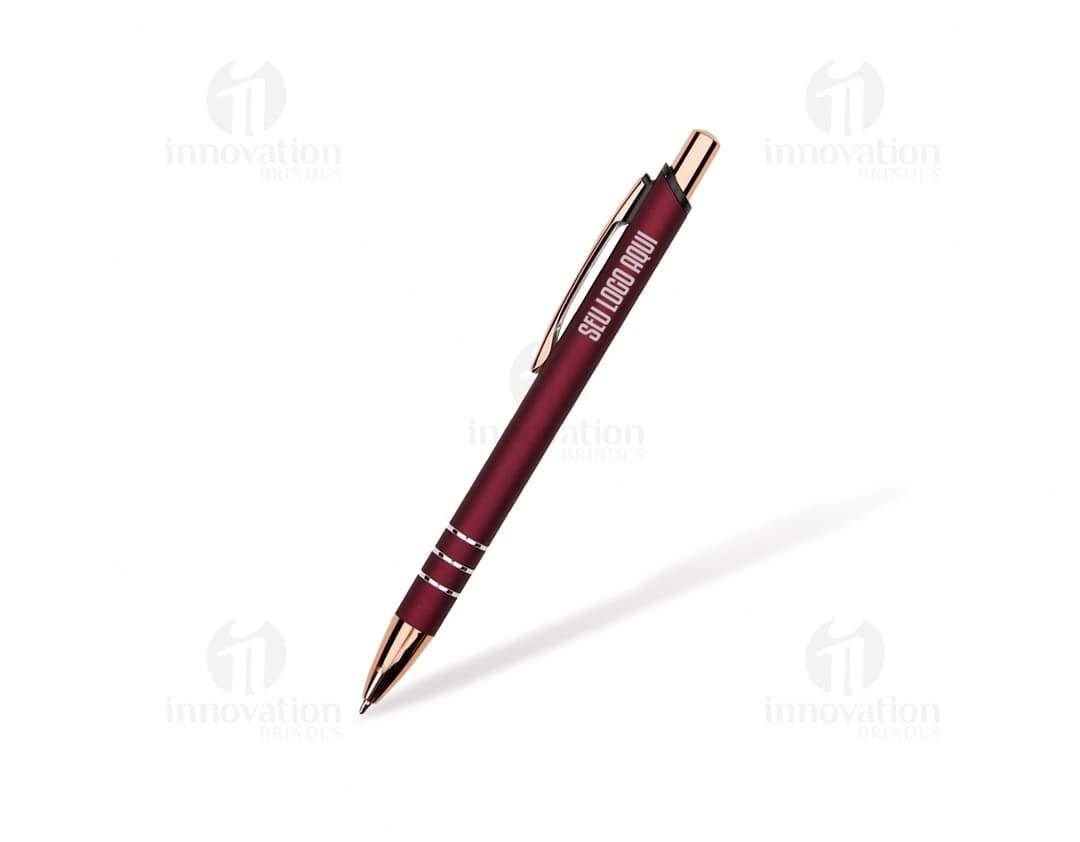 Caneta de metal prateada sobre um papel em branco, ao lado de um caderno de anotações e outros objetos de escritório.