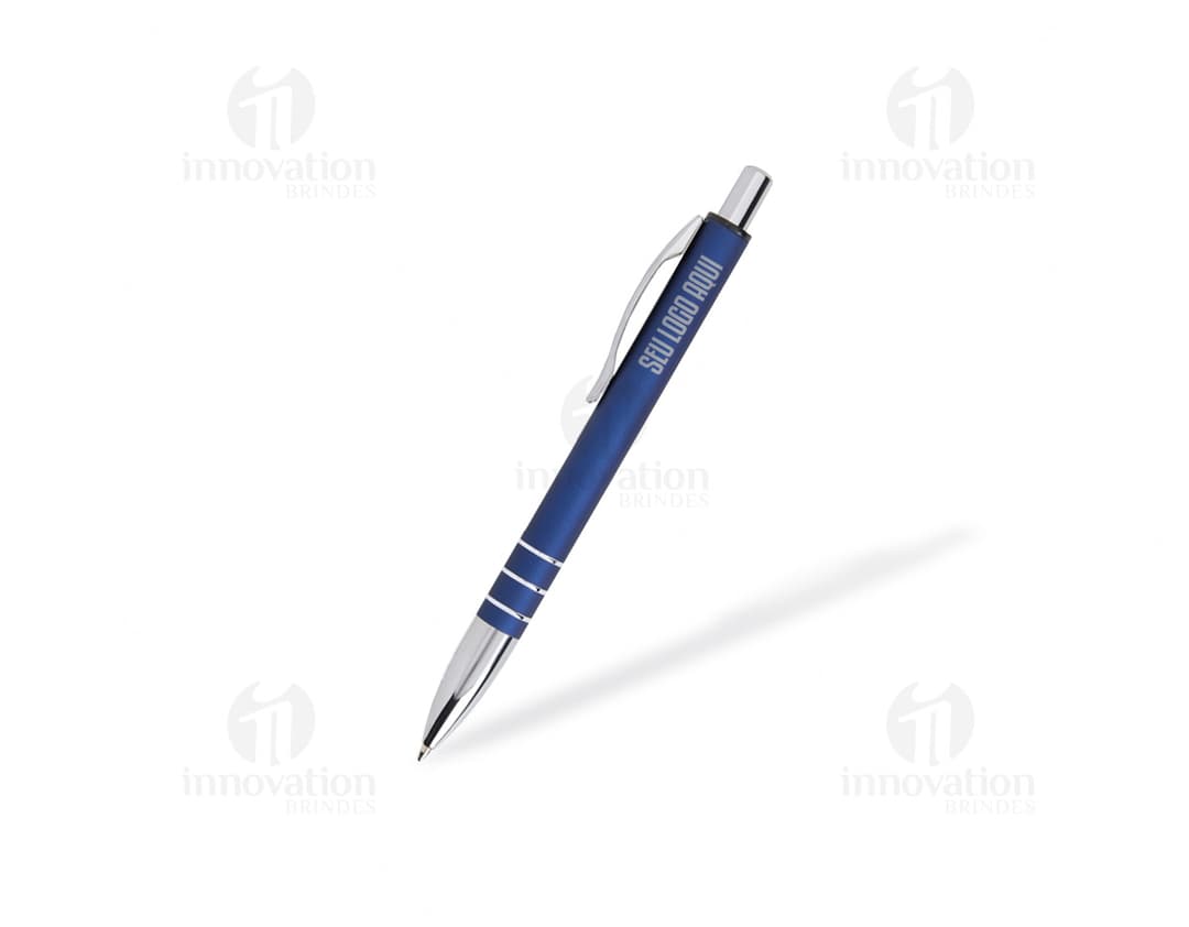 Caneta de metal prateada, com design clássico e detalhes em dourado. A imagem mostra o utensílio de escrita de perto, destacando o material metálico e a ponta afiada da caneta.