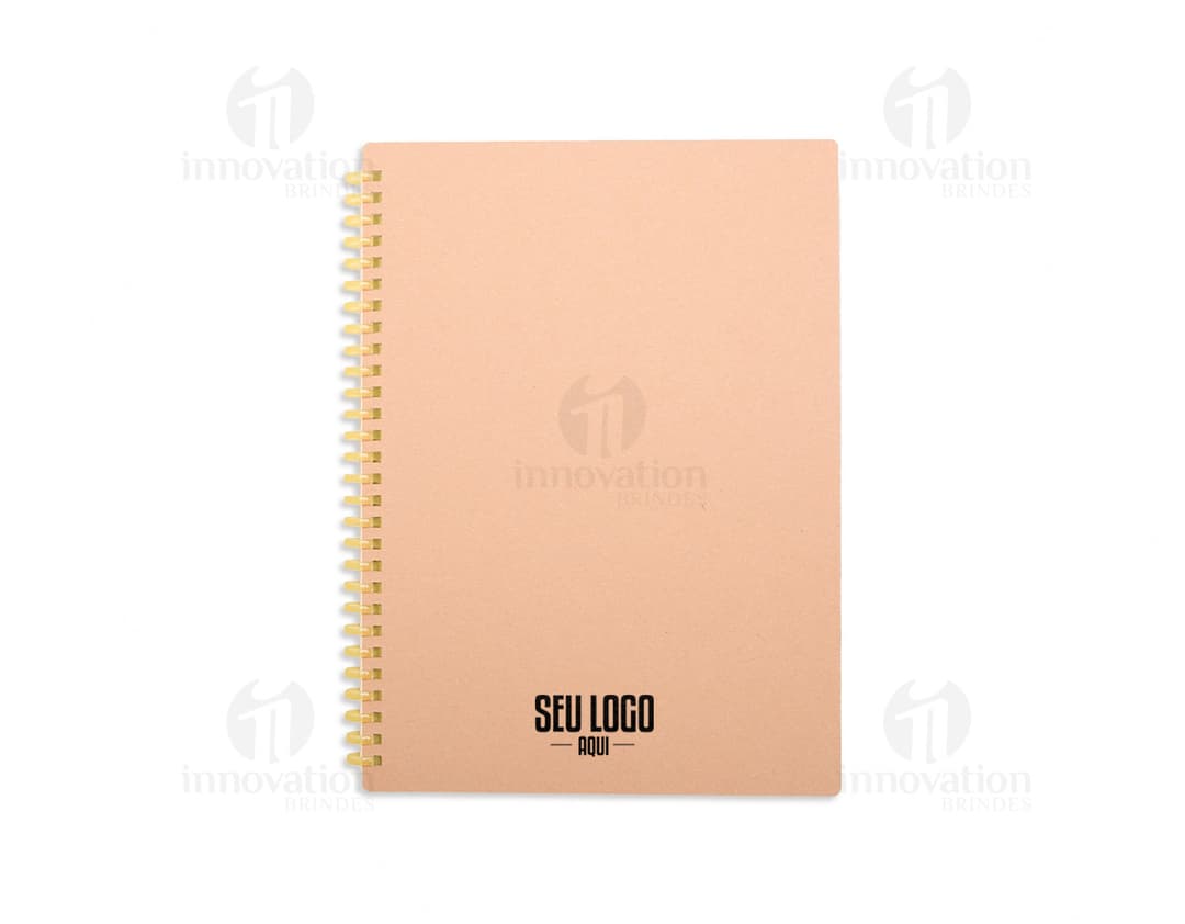 Caderno Kraft com design em papel kraft em branco, dentro de um envelope vazio de papelão. O notebook está aberto mostrando páginas em branco. Em volta, há outros objetos de papelaria e embalagens vazias.